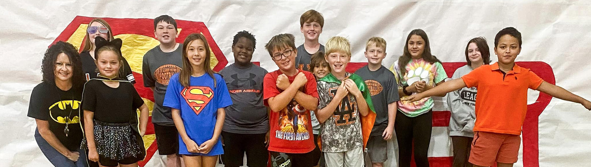 Happy group of elementary students with teacher dressed as super heroes