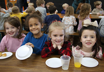 Four happy girls sitting at the lunch table