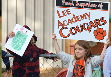 Elementary girl holding up Lee Academy Cougars poster
